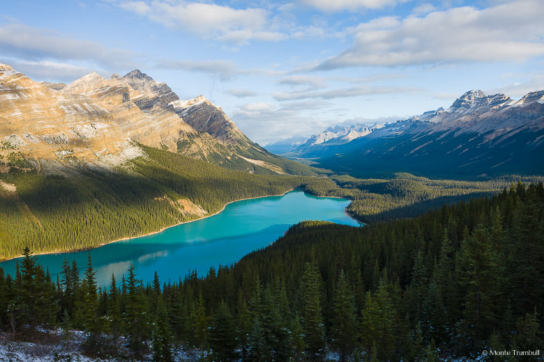 Sunrise spills into the mountainous valley and illuminates the aqua colored water of Peyto Lake in Banff National Park, Canada.