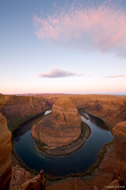 The first light of dawn bathes Horseshoe Bend and the clouds above in a soft, serene pink light outside of Page, Arizona.