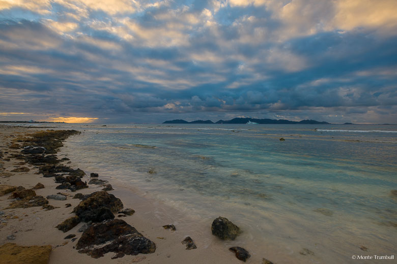 The rising sun illuminates the tops of heavy rain clouds at Merrywing Bay in Anguilla, BWI.