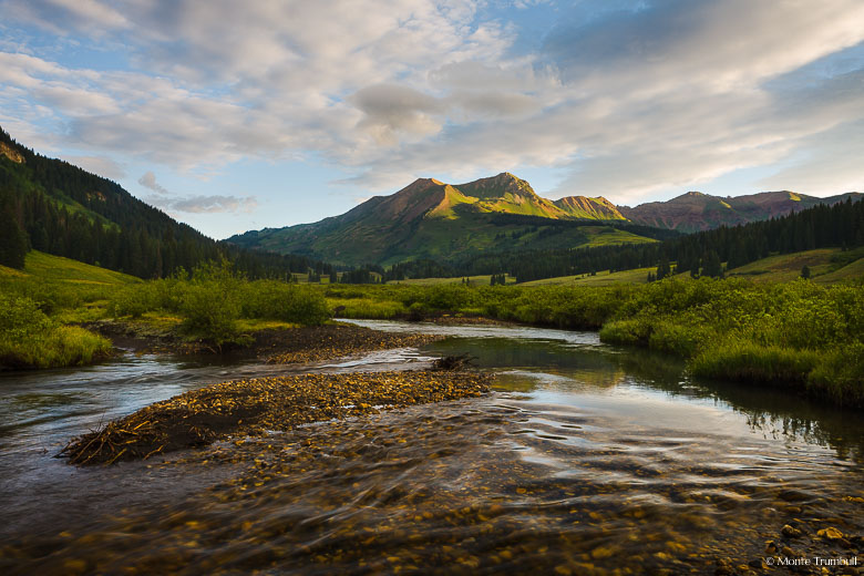 Sunlight reaches the peak of Mount Bellview rising above the East River outside of Gothic, Colorado.