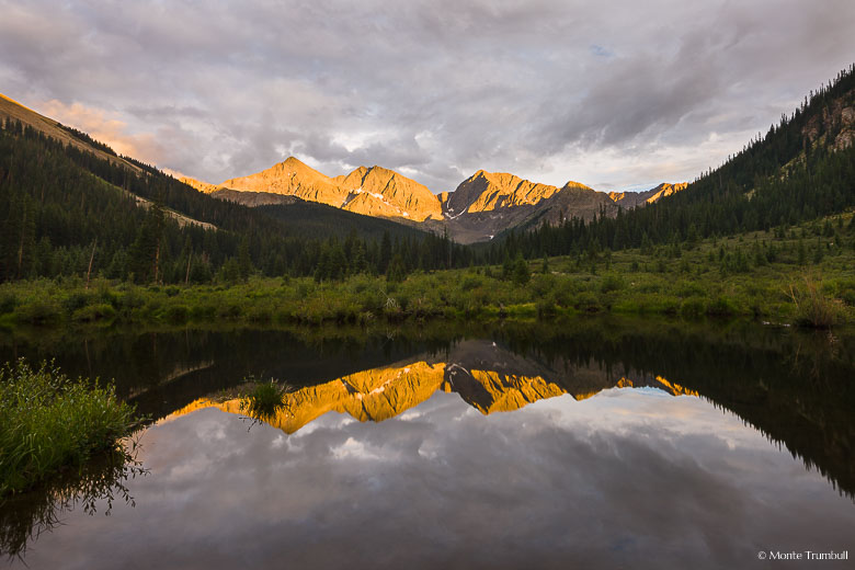 The setting sun illuminates the Three Apostles that are reflected in a beaver pond in Clear Creek Canyon outside of Buena Vista, Colorado.