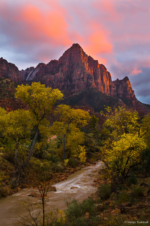 An ominous sky clears enough to let the setting sun through to illuminate The Watchman and the clouds above in Zion National Park, Utah.