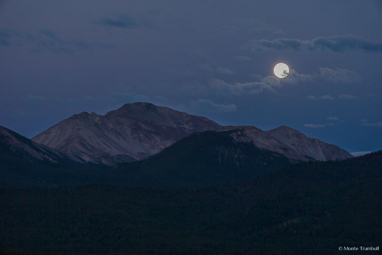 The full moon sets over Mount Yale in the purple skies of twilight outside of Buena Vista, Colorado.