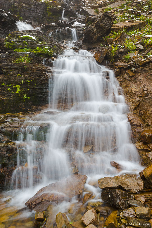 The headwaters of Logan Creek fan out and flow over Oberlin Falls high up in the mountains of Glacier National Park.