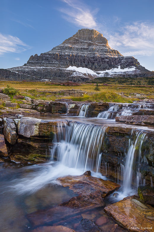 Reynolds Creek drops over a rocky shelf in the alpine tundra below Reynolds Mountain illuminated by the fading light of dusk in Glacier National Park, Montana.