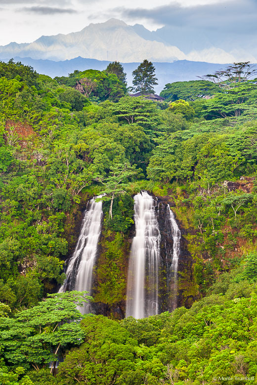 The Mahaleha Mountains emerge from rain clouds behind Opaekaa Falls dropping into a lush valley in Kauai, Hawaii.