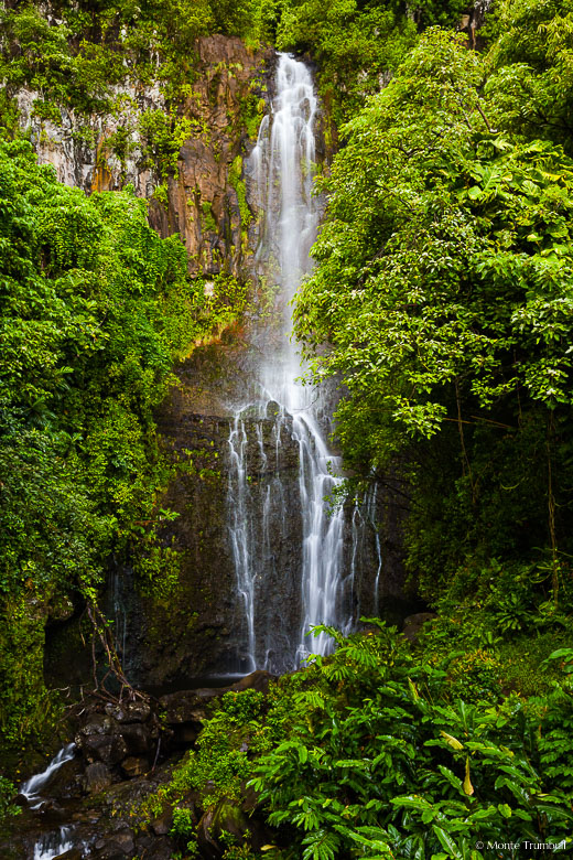 Honolewa Stream emerges from thick vegetation and gracefully tumbles down Paihi Falls outside of Hana on the Hawaiian Island of Maui.