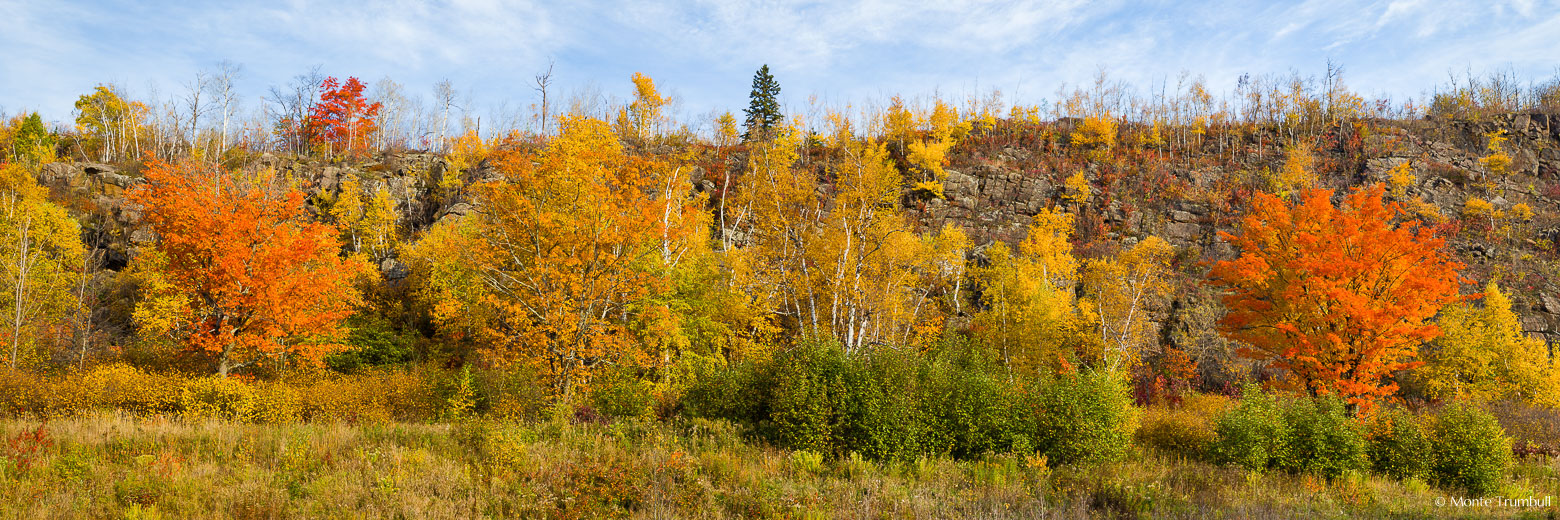 A rocky hillside is covered with a variety of trees and shrubs at the peak of fall color outside of Silver Bay on the North Shore of Minnesota.