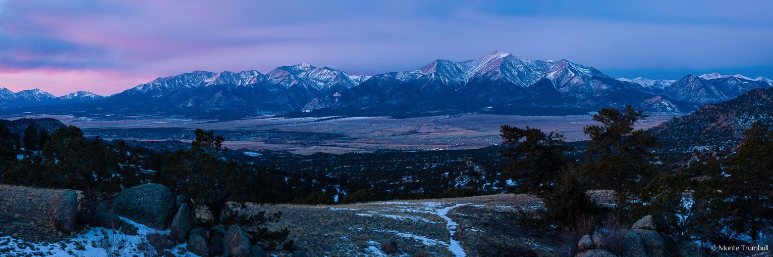 The Arkansas River valley and the Sawatch Mountains in the distance are bathed in soft pink light at dawn on a winter morning outside of Buena Vista, Colorado.