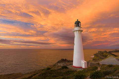 The rising sun illuminates the clouds behind Castlepoint Lighthouse on the North Island of New Zealand.