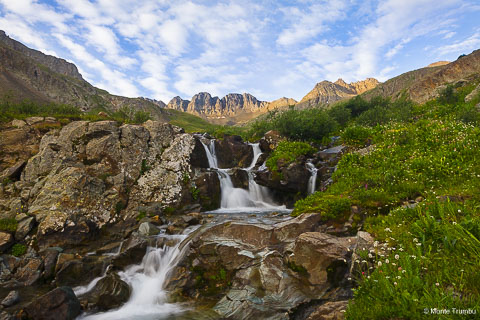 First light shines on the San Juan Mountains above a small waterfall in American Basin in southwestern Colorado.